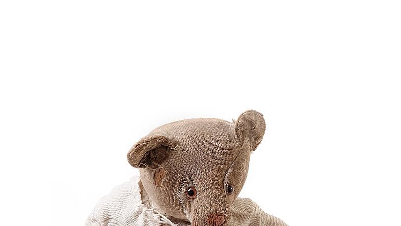 Eigentlich gehörte der Teddy von Friederike Niesner einmal ihrer Schwester. Neu war er im Jahr 1935, etwas ramponiert sah er jedoch schon sehr bald aus: Ihre Schwester entschloss sich, in der Küche Friseur zu spielen und schnitt dem Bären sämtliche Haare am Kopf ab. Kahl geschoren ging das arme Stofftier einige Jahre später in den Besitz von Friederike über.
Im April 1945 verlassen sie und ihre Familie das tschechische Brünn per Lastwagen – wobei ihr „Tedy“, mit langem ,e’ gesprochen, natürlich nicht fehlen darf. Sie steckt ihn in ihren Rucksack und lässt nur den kahlen Kopf herausschauen. Über Iglau und Strobnitz gelangt die Familie schließlich nach Langstrobnitz. Am 8. Mai marschieren Russen ins Dorf. Als einige Tage später die Tschechen folgen, sollen Friederike Niesners Familie bis Mitternacht das Land verlassen. Ihre Mutter protestiert heftig – und hat Erfolg: Ein Bauer fährt sie an die österreichische Grenze. In der Praxis eines Wiener Zahnarzts finden sie Unterschlupf. Nach 5 Jahren übersiedeln ihre Eltern, sie und der Teddybär nach Bayern. Noch heute sitzt er auf Niesners Couch und lächelt. Mitgenommen, aber treuherzig. Eigentlich gehörte der Teddy von Friederike Niesner einmal ihrer Schwester. Neu war er im Jahr 1935, etwas ramponiert sah er jedoch schon sehr bald aus: Ihre Schwester entschloss sich, in der Küche Friseur zu spielen und schnitt dem Bären sämtliche Haare am Kopf ab. Kahl geschoren ging das arme Stofftier einige Jahre später in den Besitz von Friederike über.
Im April 1945 verlassen sie und ihre Familie das tschechische Brünn per Lastwagen – wobei ihr „Tedy“, mit langem ,e’ gesprochen, natürlich nicht fehlen darf. Sie steckt ihn in ihren Rucksack und lässt nur den kahlen Kopf herausschauen. Über Iglau und Strobnitz gelangt die Familie schließlich nach Langstrobnitz. Am 8. Mai marschieren Russen ins Dorf. Als einige Tage später die Tschechen folgen, sollen Friederike Niesners Familie bis Mitternacht das Land verlassen. Ihre Mutter protestiert heftig – und hat Erfolg: Ein Bauer fährt sie an die österreichische Grenze. In der Praxis eines Wiener Zahnarzts finden sie Unterschlupf. Nach 5 Jahren übersiedeln ihre Eltern, sie und der Teddybär nach Bayern. Noch heute sitzt er auf Niesners Couch und lächelt. Mitgenommen, aber treuherzig.