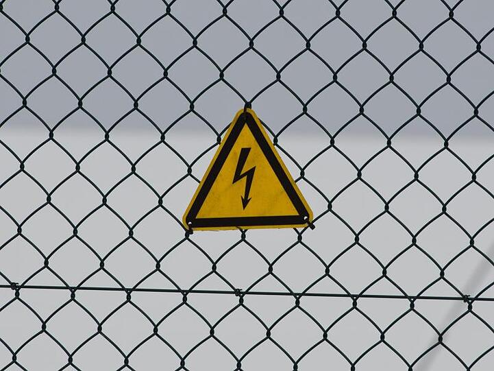 Ein Warnschild warnt an einem Zaun vor Strom. Foto: Armin Weigel/Archiv