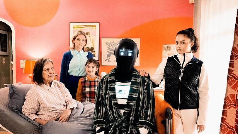 Gruppenbild mit Roboter: Frau Winkler (Angela Winkler), Tochter (Laura Tonke) und Enkelin (Zoë Baier) mit Pawlowitsch (Josef Ellers) im Morgenmantel und Pflegeroboter-Vertreterin Selma (Via Jikeli). Gruppenbild mit Roboter: Frau Winkler (Angela Winkler), Tochter (Laura Tonke) und Enkelin (Zoë Baier) mit Pawlowitsch (Josef Ellers) im Morgenmantel und Pflegeroboter-Vertreterin Selma (Via Jikeli).