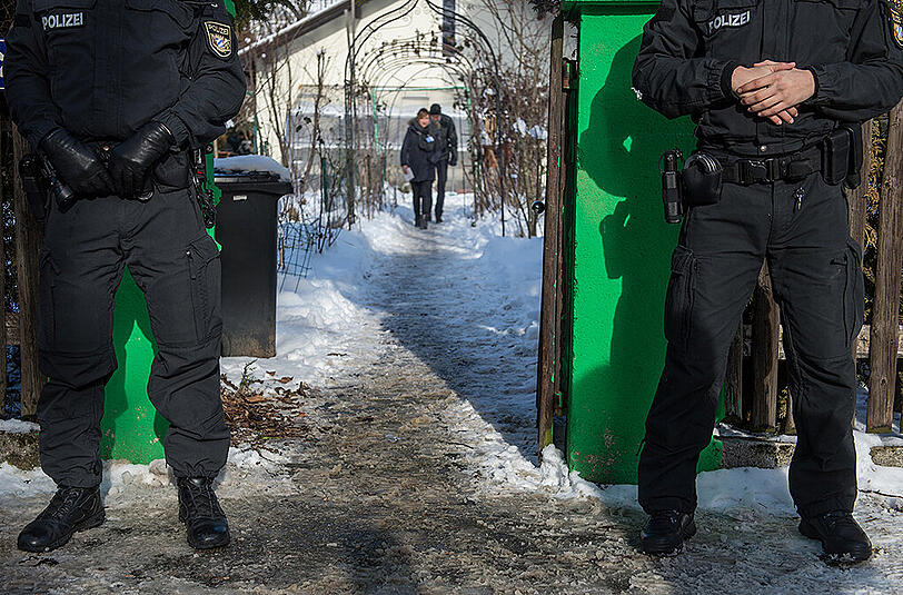 Polizisten stehen vor dem Haus, in dem sich die schreckliche Tat ereignete.
