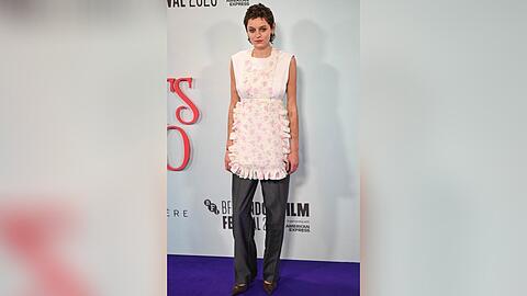 Schauspielstar Emma Corrin mit Blumenschürze auf dem roten Teppich.