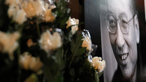 Das Porträt des verstorbenen chinesischen Friedensnobelpreisträger Liu Xiaobo ist in Hongkong vor dem Verbindungsbüro Peking neben Blumen zu sehen.