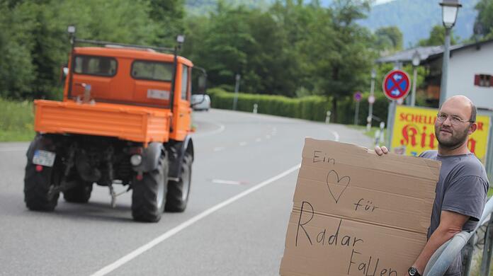 Tobias Anzenberger hat sich mit seiner Papp-Warnung an der Straße platziert. Er muss das Schild halten, sonst wäre es eine Ordnungswidrigkeit.