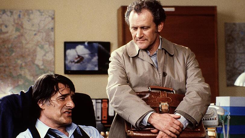 Der Monaco Franze (Helmut Fischer) mit Karl Obermayr in seiner Rolle als Spezl Manni Kopfeck. In einer Folge treibt der Monaco einen Beamten fast in den Wahnsinn, weil er seine Pension unbedingt in bar ausgezahlt haben will. Das geht jetzt bei der Deutschen Bank nicht mehr.