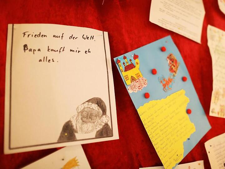 Ein Wunschzettel mit dem Satz "Frieden auf der Welt - Papa kauft mir eh alles" hängt in der Christkind-Postfiliale an der Wand.