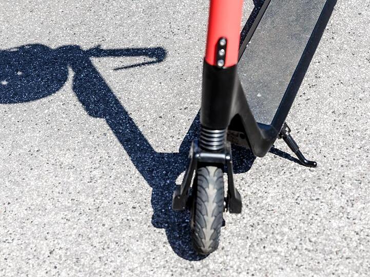 Der Schatten eines Herlmes am Griff eines Elektro-Tretrollers. Foto: Markus Scholz/Archivbild