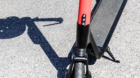 Der Schatten eines Herlmes am Griff eines Elektro-Tretrollers. Foto: Markus Scholz/Archivbild