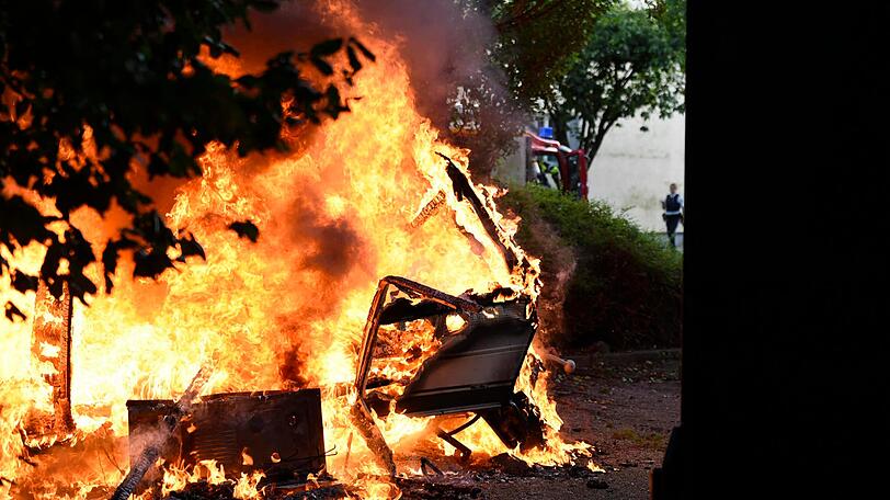 Feuerwehrkräfte mit schwerem Atemschutz löschen den Wohnwagen unter der Eisenbahnbrücke in Untergiesing.