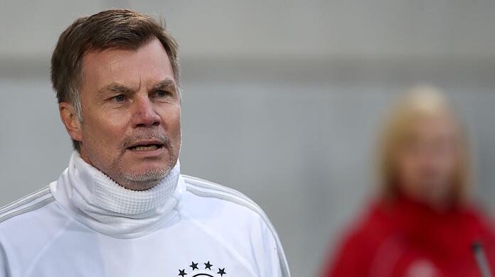 Thomas Helmer steht beim Aufwärmtraining auf dem Platz.