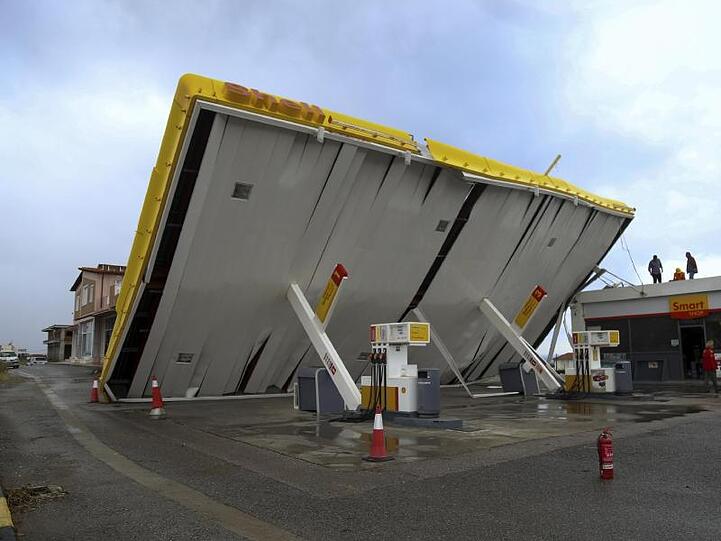 Arbeiter überprüfen die Sturmschäden an einer Tankstelle.