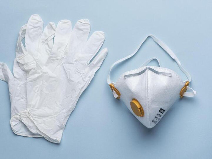 Eine Atemschutzmaske der Kategorie FFP3 und Einweghandschuhe liegen auf einem Tisch. Foto: Christian Beutler/KEYSTONE/dpa/Illustration