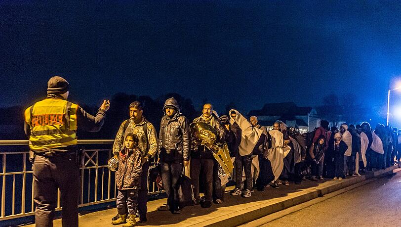 Ein Polizist nimmt bei Simbach am Inn an der deutsch-österreichischen Grenze eine Gruppe von Flüchtlingen in Empfang. Ein Polizist nimmt bei Simbach am Inn an der deutsch-österreichischen Grenze eine Gruppe von Flüchtlingen in Empfang.