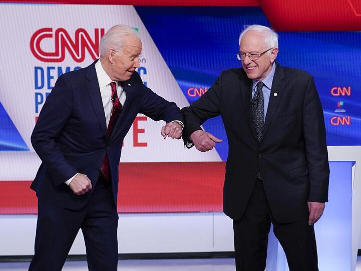 Bernie Sanders (r), und Joe Biden begrüßen sich mit ihren Ellenbogen.