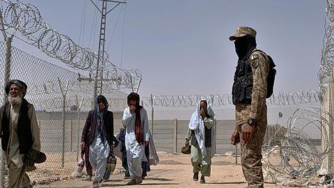 Ein pakistanischer Soldat steht Wache, während Menschen aus Afghanistan über einen Grenzübergang in Chaman nach Pakistan einreisen.