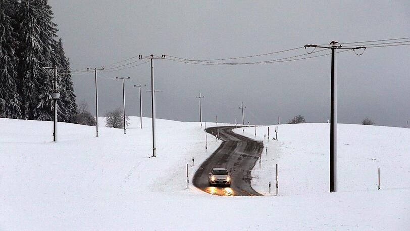 Ein Auto fährt durch die schneebedeckte Allgäuer Landschaft bei Görisried.