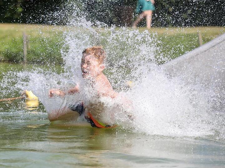 So lässt sich die Hitze aushalten: Ein Junge rutscht eine Wasserrutsche hinunter.