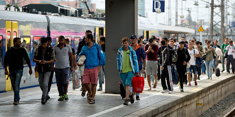Flüchtlinge, die kurz zuvor mit einem Zug aus Salzburg angekommen sind, gehen auf dem Hauptbahnhof über einen Bahnsteig.