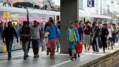 Flüchtlinge, die kurz zuvor mit einem Zug aus Salzburg angekommen sind, gehen auf dem Hauptbahnhof über einen Bahnsteig.