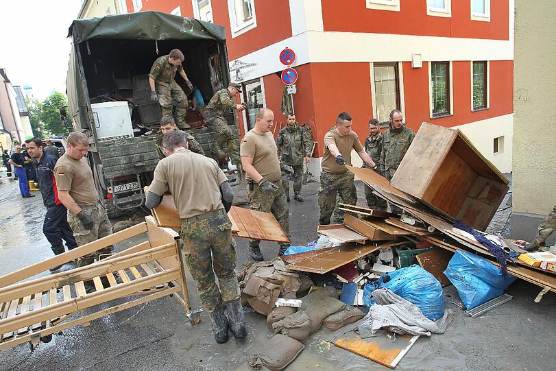 Das große Aufräumen in Passau: Helfer kämpfen gegen den Schlamm, auf den Straßen stehen zerstörte Möbel.