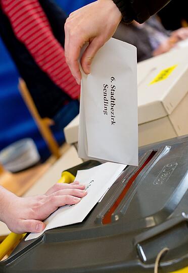 Eine Frau wirft am 16.03.2014 im Wahllokal in der Grundschule an der Plinganserstrasse in München (Bayern) ihren Stimmzettel in eine Wahlurne.