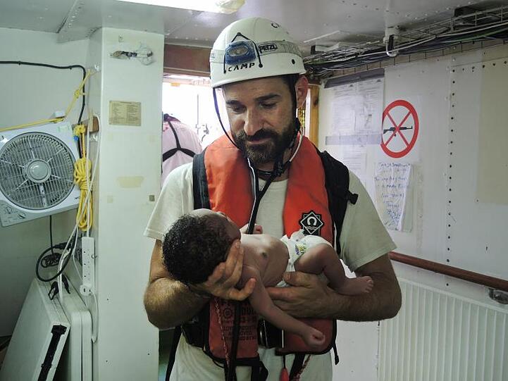 Ein Arzt der Hilfsorganisation Ärzte ohne Grenzen hält an Bord der "Aquarius" ein gut eine Woche altes Baby, das von einem Schlauchboot im Mittelmeer gerettet wurde.