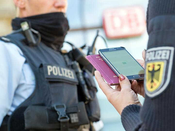 Eine Bundespolizistin scannt mit einem Mobiltelefon einen Reisepass.
