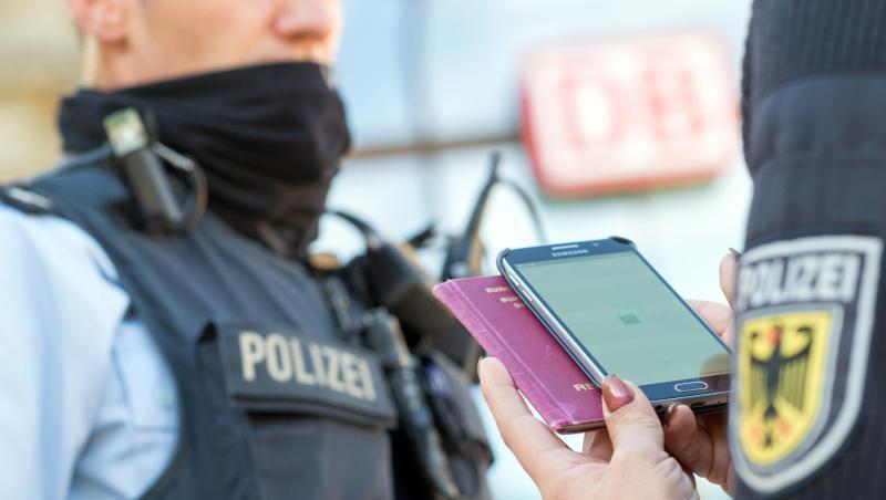 Eine Bundespolizistin scannt mit einem Mobiltelefon einen Reisepass.