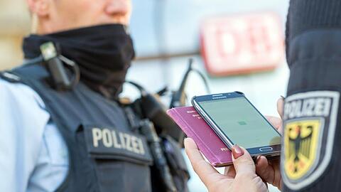 Eine Bundespolizistin scannt mit einem Mobiltelefon einen Reisepass.