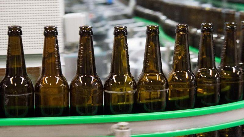 Gewaschene Bierflaschen laufen durch die Produktion einer Brauerei. Foto: Rainer Jensen/Archivbild