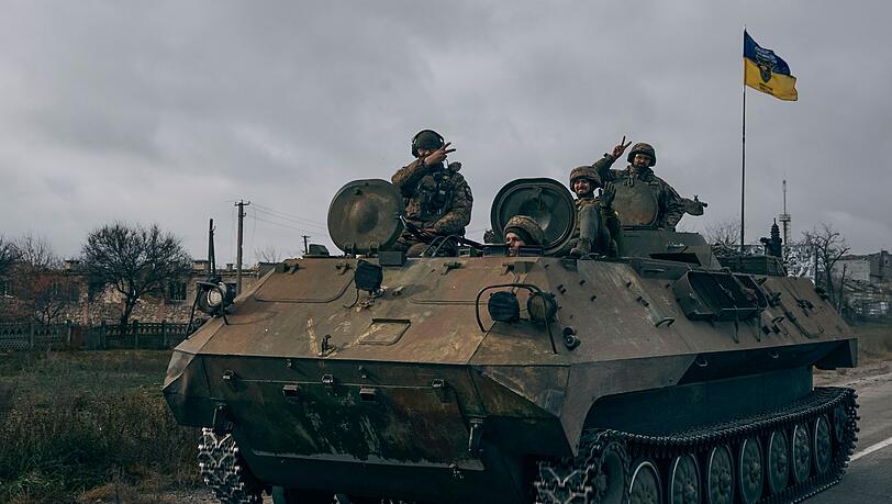 Ukrainische Soldaten zeigen ein Victory-Zeichen während sie mit einem erbeuteten russischen Schützenpanzer fahren.