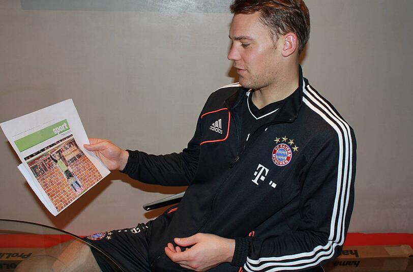 Manuel Neuer blickt auf eine Fotomontage der Abendzeitung, die ihn im Tor des FC Bayern vor einer Mauer zeigt.