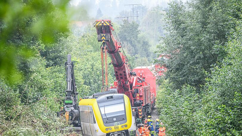 Mit einem Kran wird an der Unfallstelle, an der ein Regionalzug entgleist ist, gearbeitet. Ein Regionalexpress war am Sonntagabend (27.07.2025) in Riedlingen nach bisherigen Erkenntnissen infolge eines Hangrutsches entgleist.