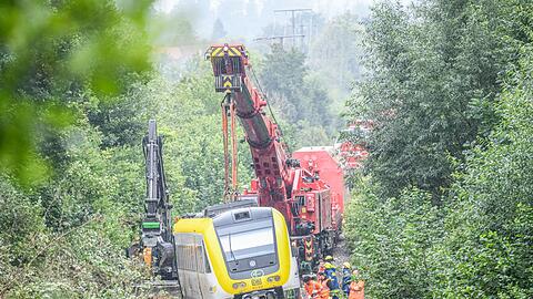 Mit einem Kran wird an der Unfallstelle, an der ein Regionalzug entgleist ist, gearbeitet. Ein Regionalexpress war am Sonntagabend (27.07.2025) in Riedlingen nach bisherigen Erkenntnissen infolge eines Hangrutsches entgleist.