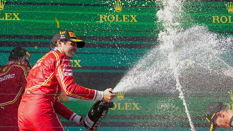 Ferrari-Pilot Carlos Sainz feiert mit Champagner seinen Sieg.