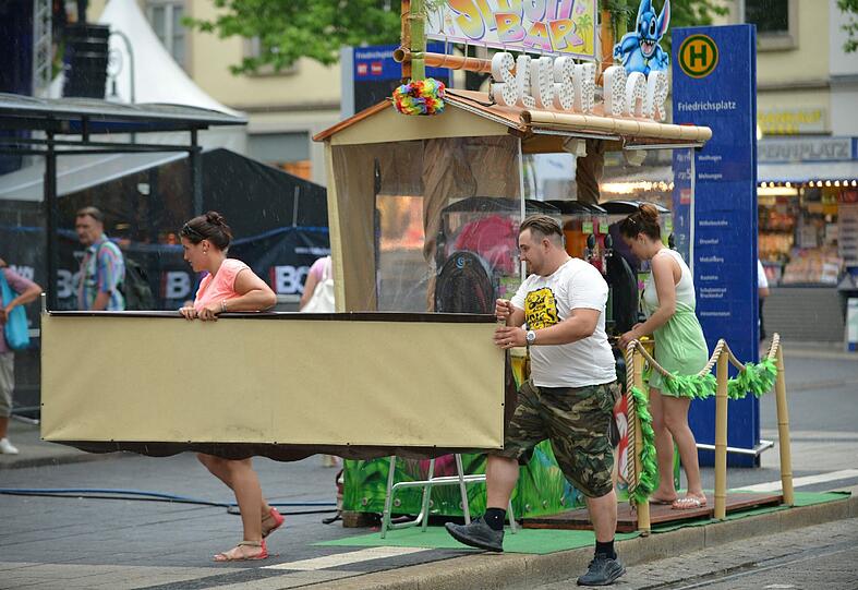 Aus Furcht vor Sturmböen bringen Standbetreiber am 20.06.2013 auf der Hessentagsstraße in Kassel (Hessen) bewegliche Teile ihres Stands in Sicherheit.