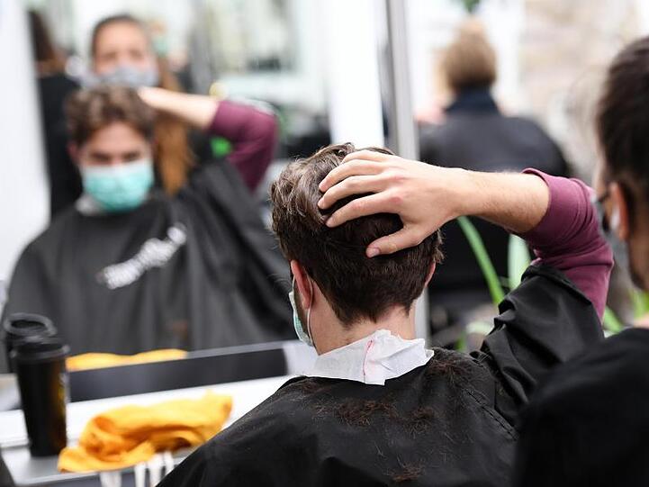Ein Kunde bekommt mit Mundschutz seine Haare geschnitten. Foto: Angelika Warmuth/dpa/Archivbild