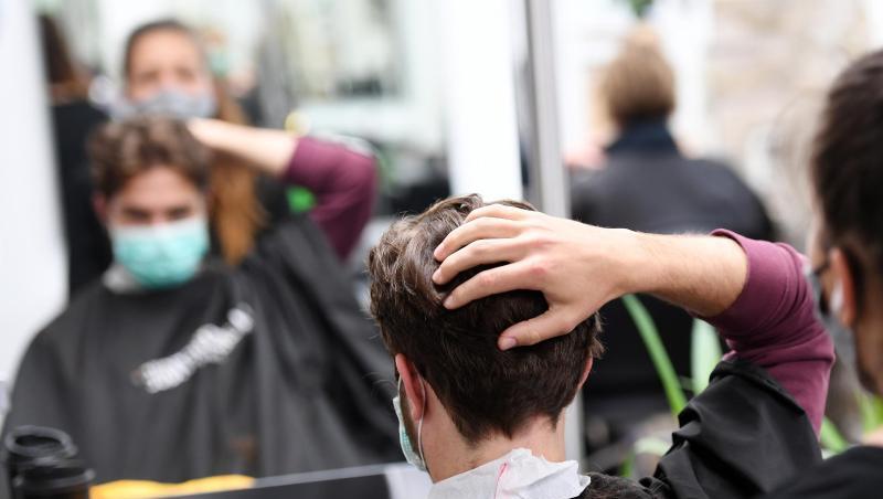 Ein Kunde bekommt mit Mundschutz seine Haare geschnitten. Foto: Angelika Warmuth/dpa/Archivbild
