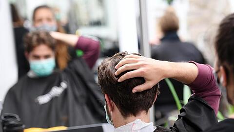 Ein Kunde bekommt mit Mundschutz seine Haare geschnitten. Foto: Angelika Warmuth/dpa/Archivbild