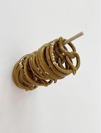 Wer Marjan Baniasadis Installation „Brezeln mit oder ohne“ von 2024 erwirbt, muss zumindest optisch nie mehr hungern und landet - Keramik macht‘s möglich - auch nicht in der Carb- oder Kohlehydrat-Falle.