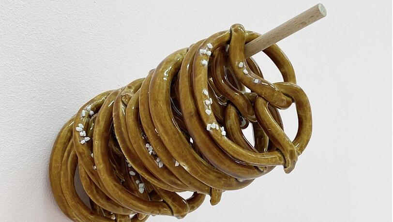 Wer Marjan Baniasadis Installation „Brezeln mit oder ohne“ von 2024 erwirbt, muss zumindest optisch nie mehr hungern und landet - Keramik macht‘s möglich - auch nicht in der Carb- oder Kohlehydrat-Falle.