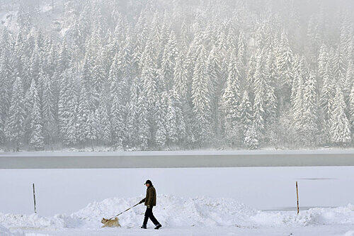 Wenn das keine Winter-Idylle ist: Dieses Herrchen und sein Hund genießen das Gassigehen am tief verschneiten Spitzingsee.