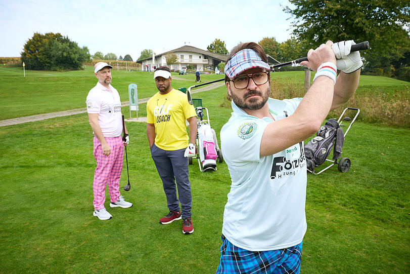 Golffieber in Niederkaltenkirchen: Simmerl (Stephan Zinner, l.) und Fl&ouml;tzinger (Daniel Christensen, r.) versuchen sich unter Aufsicht von Golflehrer Buengo (Castro Dokyi Affum, m.) auf dem Gr&uuml;n.