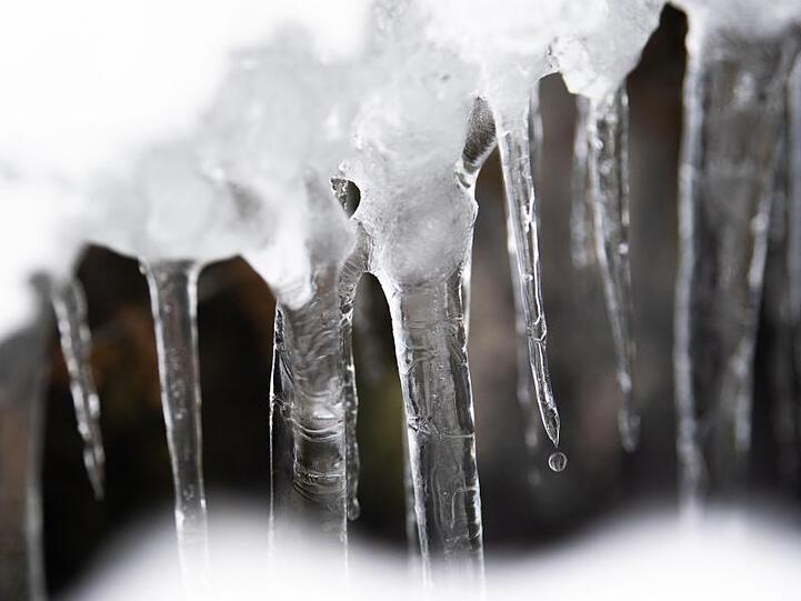 Ein Tropfen fällt von einem Eiszapfen auf den Boden. Bringt das Tauwetter in verschneiten Alpen Hochwasser? Foto: Lino Mirgeler/Archiv