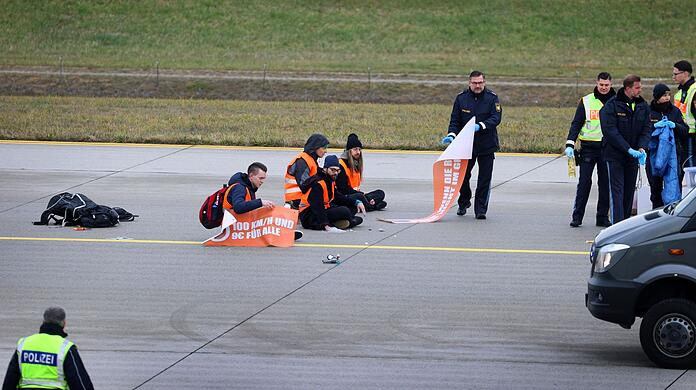 Klimaaktivisten sitzen auf dem Zubringer einer Start-und Landebahn am Airport Franz-Josef-Strauß.