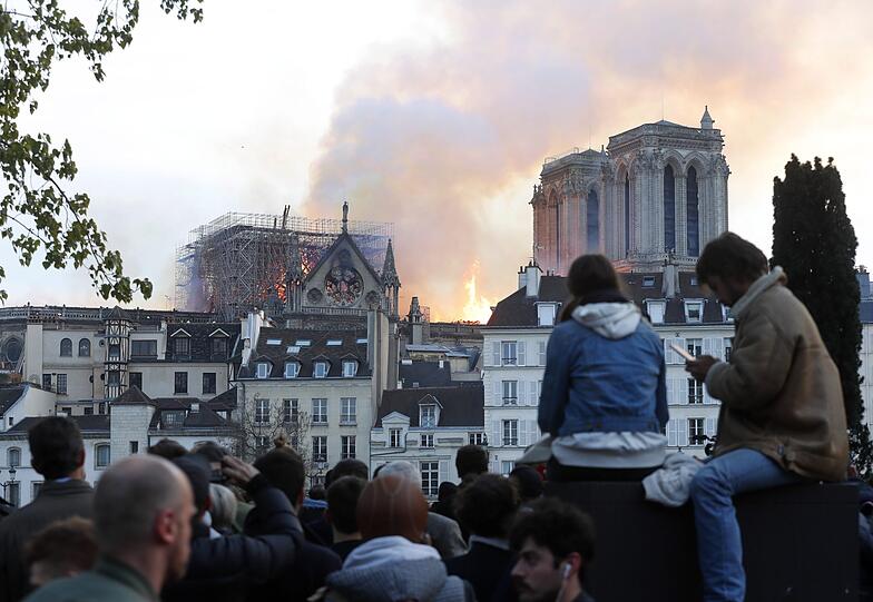 Die weltberühmte Kathedrale Notre-Dame de Paris steht in Flammen. Schaulustige haben sich versammelt.