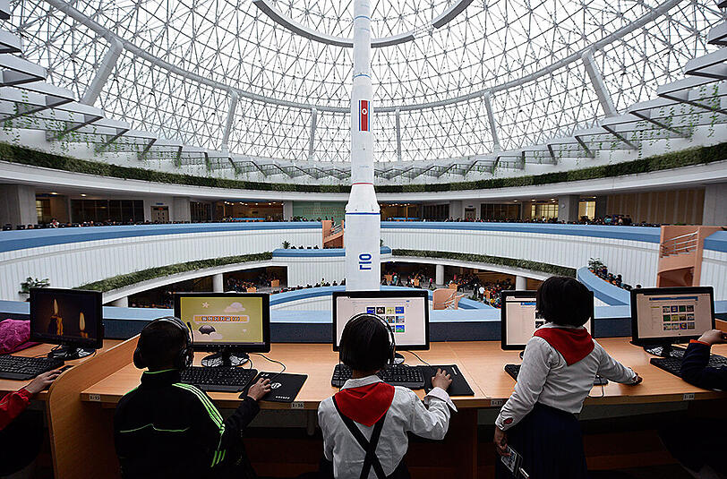 Kinder sitzen im Sci-Tech Complex in Pjöngjang an Computerarbeitsplätzen mit Blick auf eine Unha-3-Rakete. Foto: Franck Robichon/Archiv