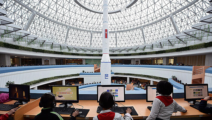 Kinder sitzen im Sci-Tech Complex in Pjöngjang an Computerarbeitsplätzen mit Blick auf eine Unha-3-Rakete. Foto: Franck Robichon/Archiv Kinder sitzen im Sci-Tech Complex in Pjöngjang an Computerarbeitsplätzen mit Blick auf eine Unha-3-Rakete. Foto: Franck Robichon/Archiv