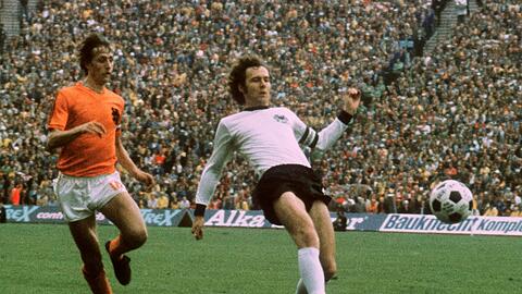 Die herausragenden Spieler dieser Generation: Der Niederländer Johan Cruyff, genannt König, und Kaiser Franz Beckenbauer, der mit Deutschland den WM-Pokal 1974 im Münchner Olympiastadion gewinnt (r.).