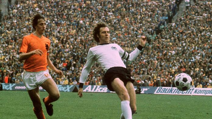 Die herausragenden Spieler dieser Generation: Der Niederländer Johan Cruyff, genannt König, und Kaiser Franz Beckenbauer, der mit Deutschland den WM-Pokal 1974 im Münchner Olympiastadion gewinnt (r.).