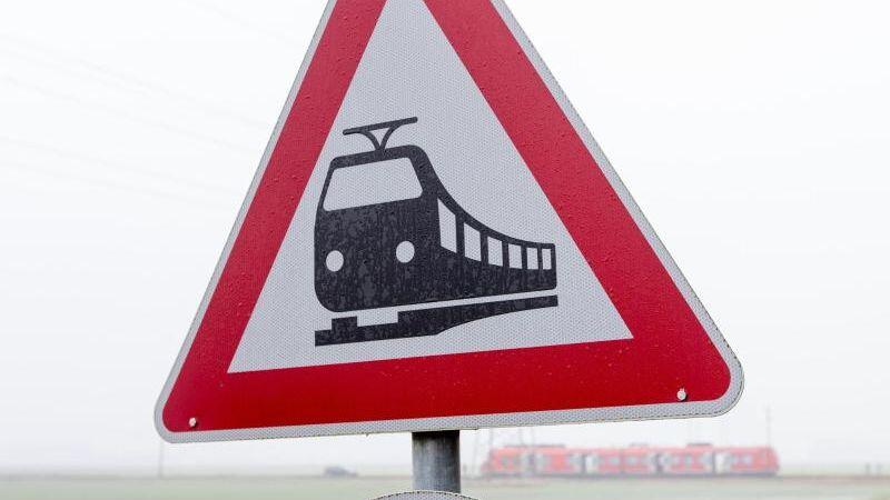 Ein Verkehrsschild im Vordergrund warnt vor Zugverkehr an einem unbeschrankten Bahnübergang. Foto: Friso Gentsch/Archiv
